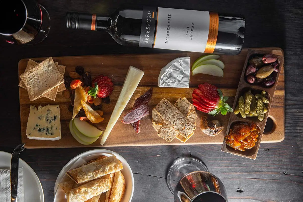 Bottle of red wine laying on a table next to a food platter