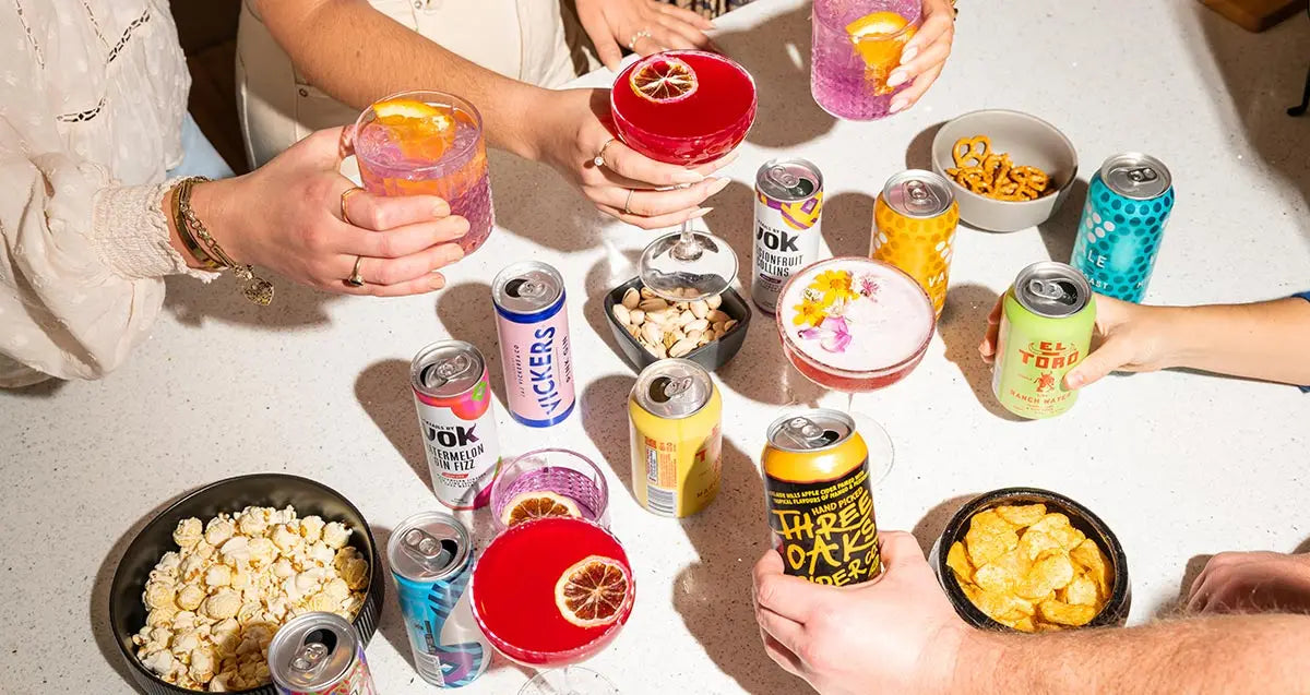 cans of beer and cider on a bench with snacks