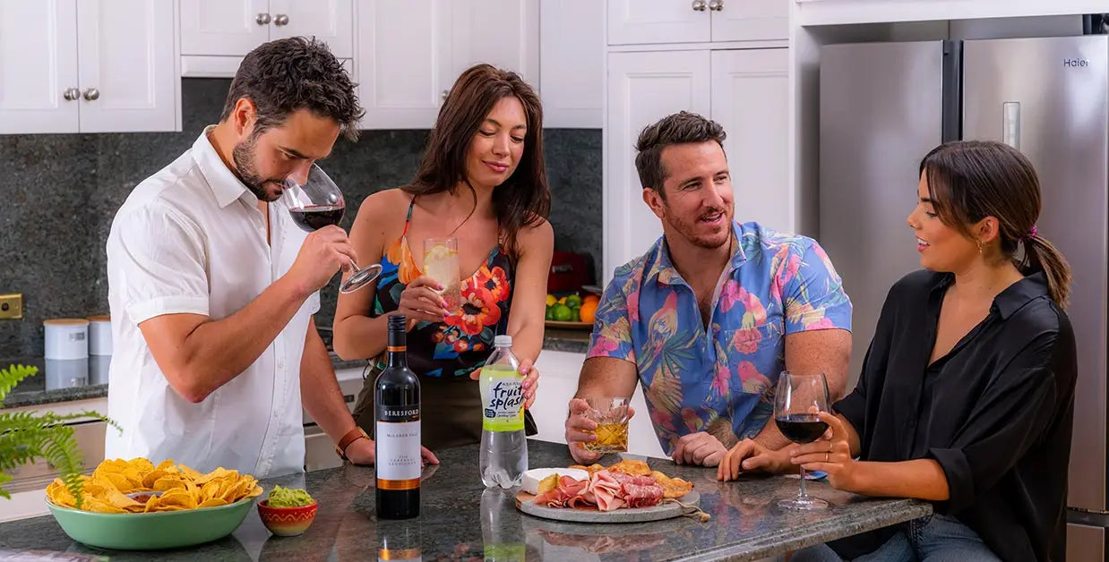 four friends enjoying at home happy hour in the kitchen