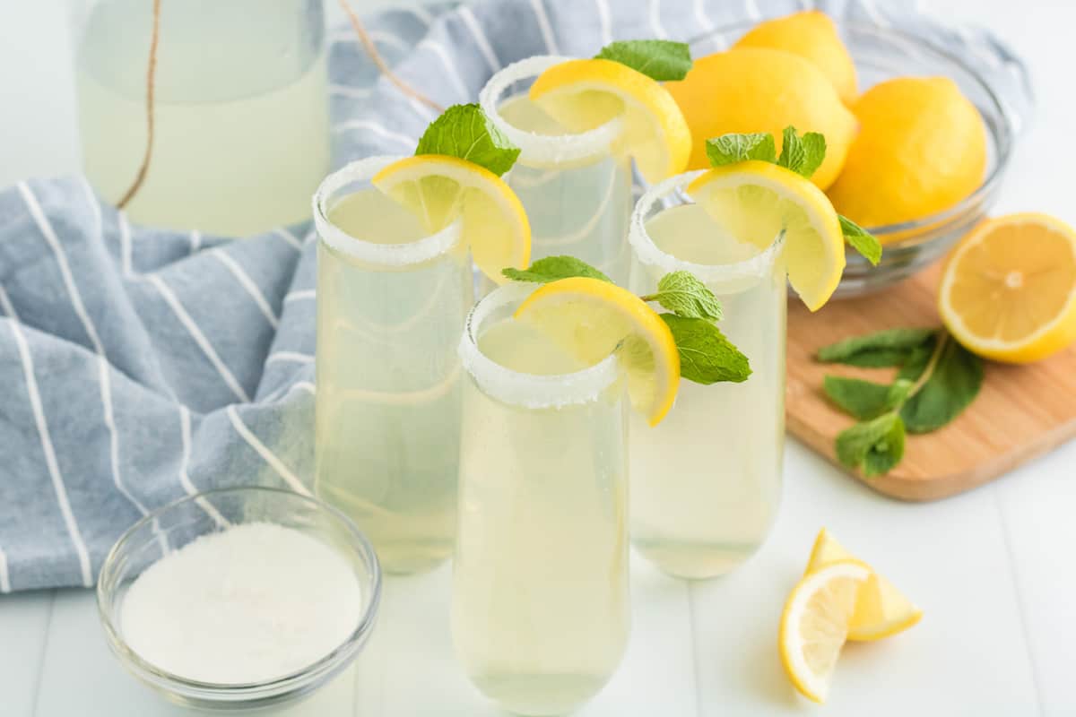 four glasses of lemonade mimosa's on a table with sliced lemon