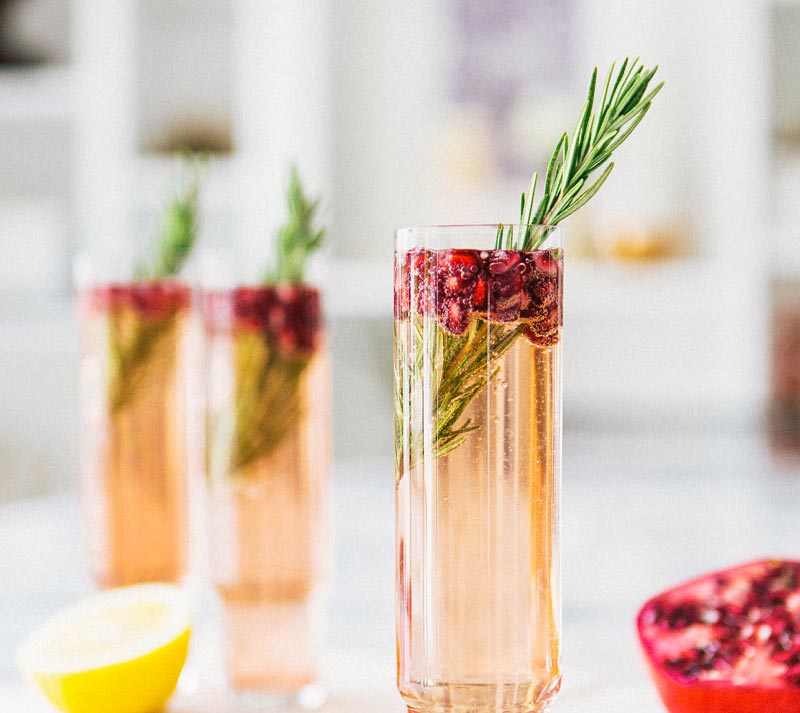 three pomegranate and rosemary spritz on a table