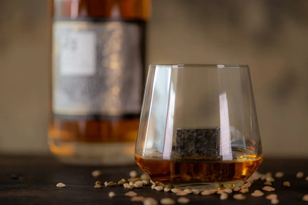 glass of whisky on a table with the bottle behind it