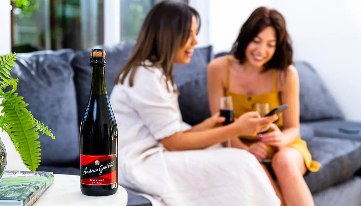 two ladies chatting on a couch with a drink