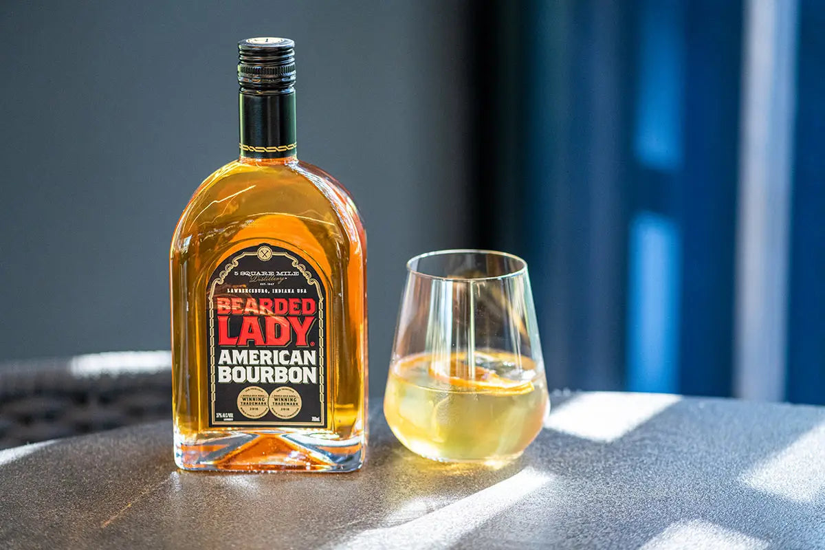 bottle of bourbon with a glass next to it on a table