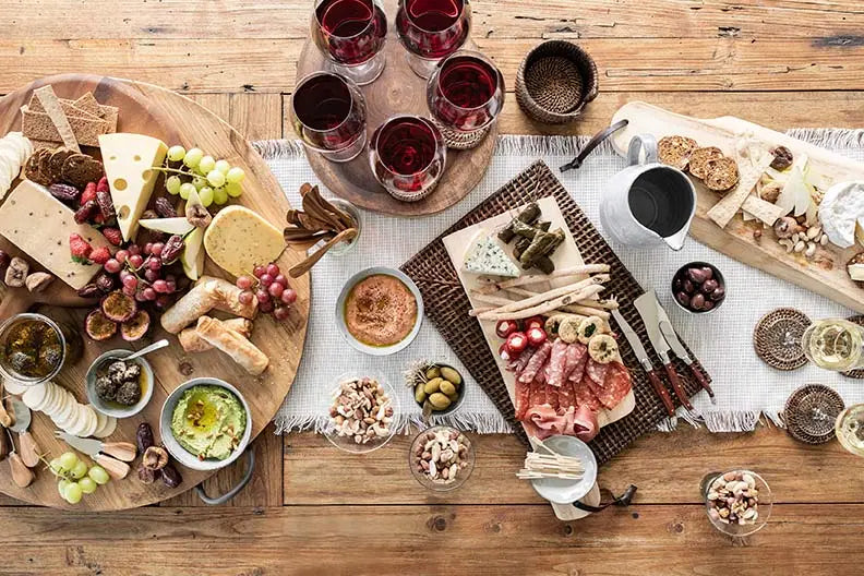 cheese platter with red wine glasses on a table top